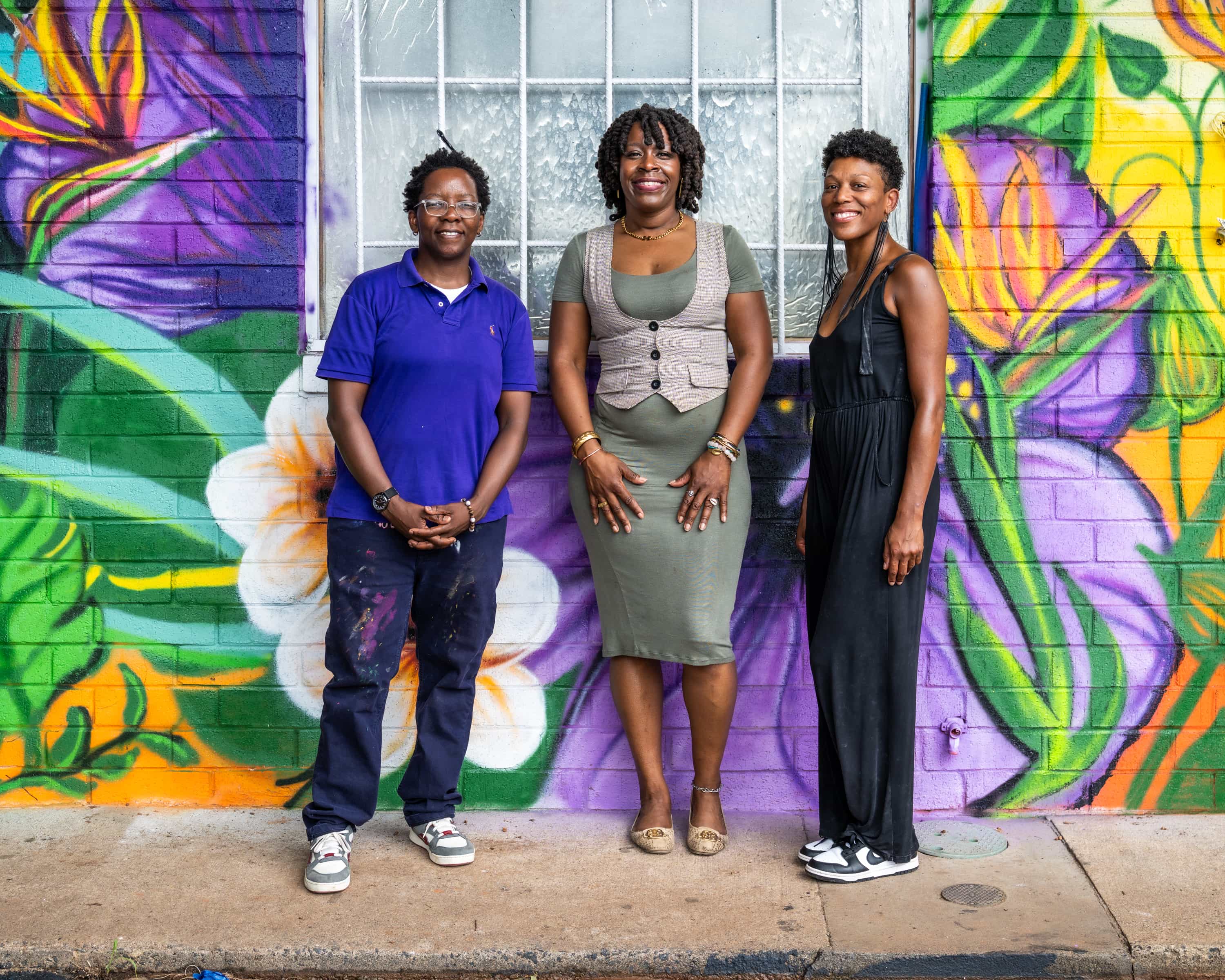 3 people in front of mural painting