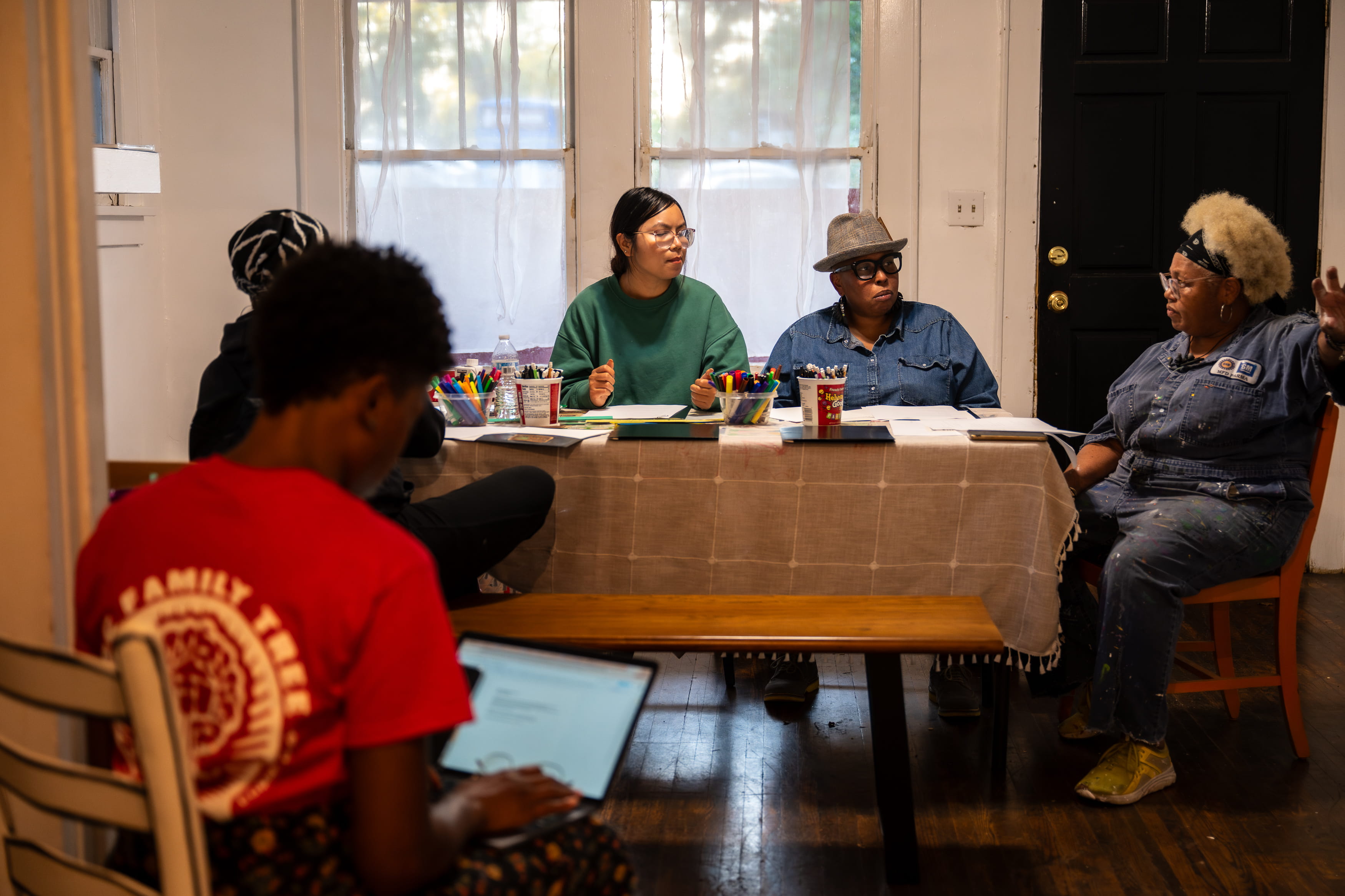 People sitting at table during meeting with art supplies on counter